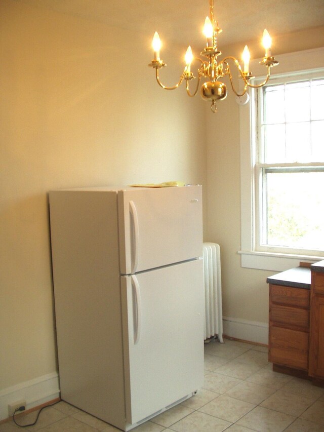 kitchen with an inviting chandelier, radiator, light tile patterned floors, and white fridge