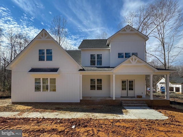 back of property with a porch and roof with shingles