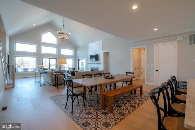 dining room with a chandelier, high vaulted ceiling, and light hardwood / wood-style flooring