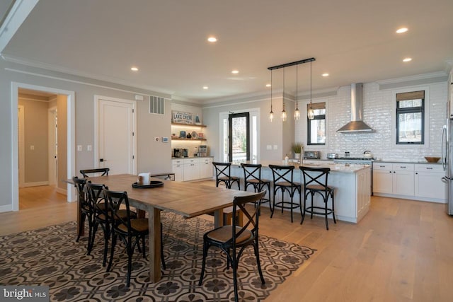 dining room featuring crown molding and light hardwood / wood-style flooring