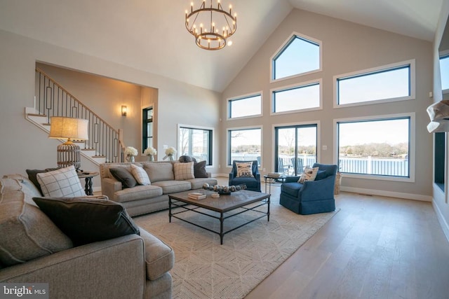 living room with plenty of natural light, a notable chandelier, high vaulted ceiling, and light hardwood / wood-style flooring