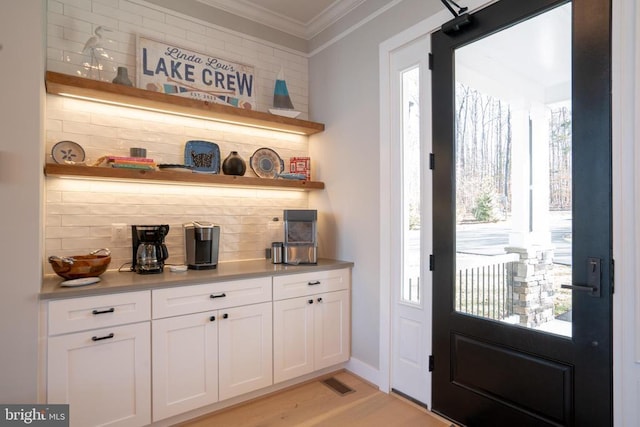 interior space with white cabinetry, crown molding, and light hardwood / wood-style floors