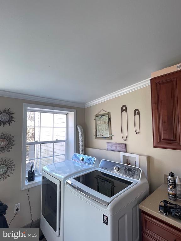 clothes washing area featuring cabinet space, ornamental molding, and independent washer and dryer