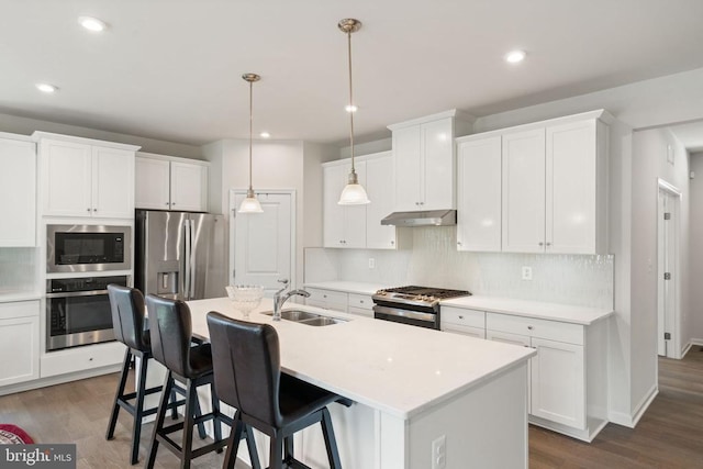 kitchen featuring stainless steel appliances, sink, a center island with sink, and white cabinets