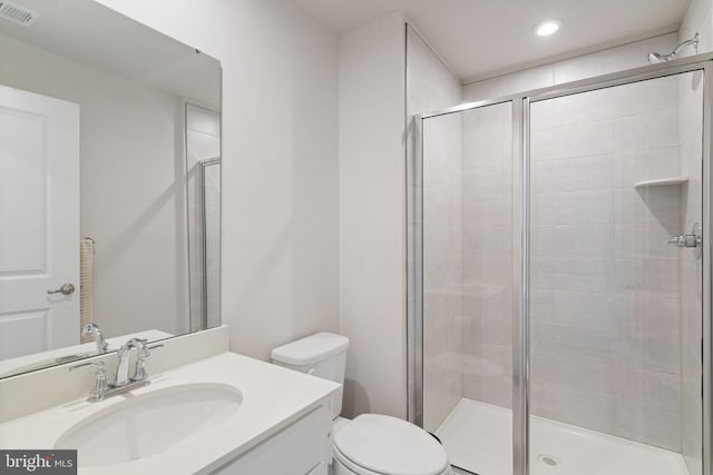 bathroom featuring vanity, toilet, and a shower with shower door