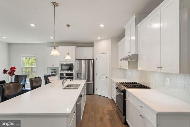 kitchen with sink, white cabinetry, stainless steel appliances, an island with sink, and decorative light fixtures