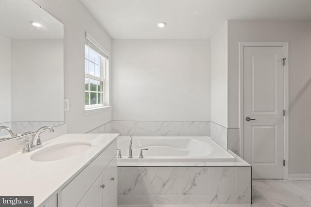 bathroom featuring a relaxing tiled tub and vanity