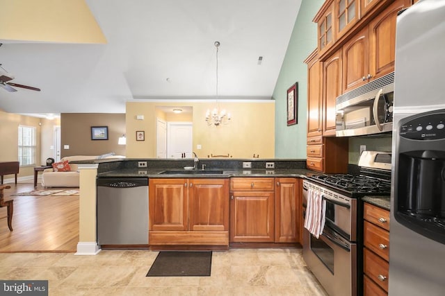 kitchen featuring brown cabinets, a sink, appliances with stainless steel finishes, a peninsula, and vaulted ceiling