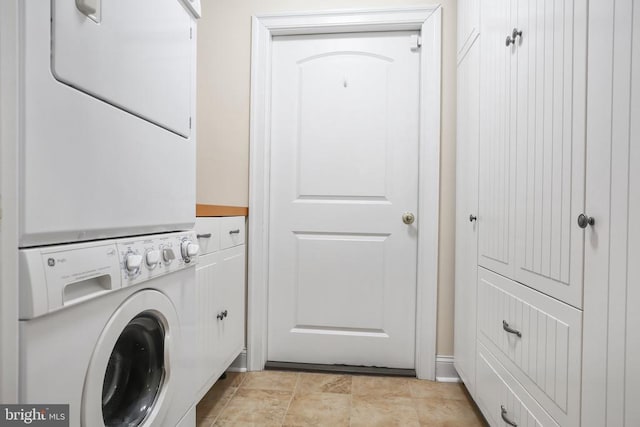 clothes washing area featuring stacked washer and dryer and cabinet space