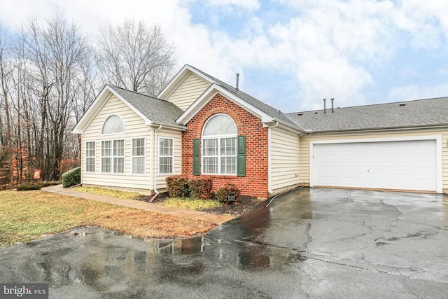 view of front of home with a front lawn, aphalt driveway, a shingled roof, a garage, and brick siding