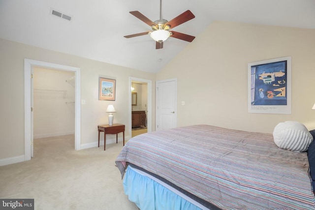 bedroom with visible vents, light carpet, a walk in closet, baseboards, and vaulted ceiling