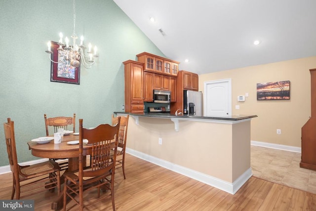 kitchen featuring dark countertops, a notable chandelier, light wood-style floors, and appliances with stainless steel finishes