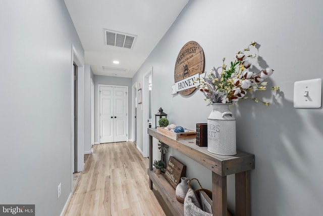 corridor featuring light wood finished floors, baseboards, and visible vents