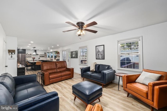 living room with baseboards, a healthy amount of sunlight, a ceiling fan, and light wood-style floors