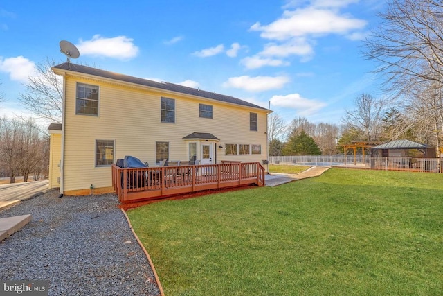 rear view of property with a wooden deck, fence, a lawn, and a gazebo