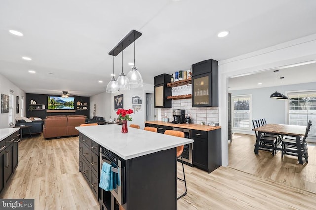 kitchen with recessed lighting, a kitchen island, light wood-style floors, tasteful backsplash, and decorative light fixtures