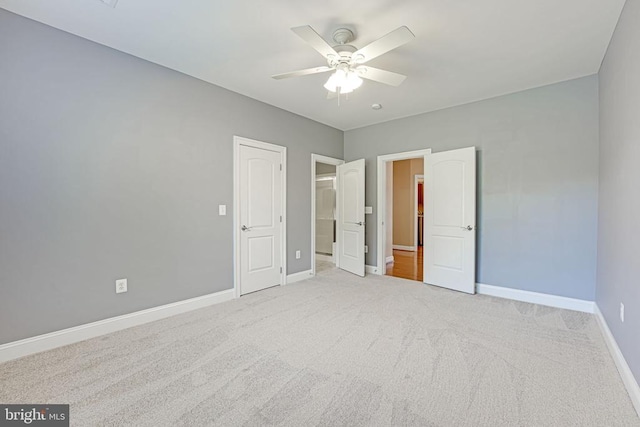 unfurnished bedroom with ceiling fan, baseboards, and light carpet