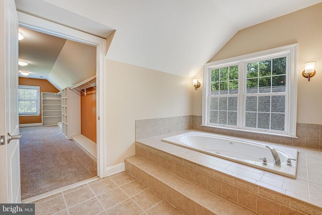 full bath with tile patterned floors, a walk in closet, baseboards, vaulted ceiling, and a bath