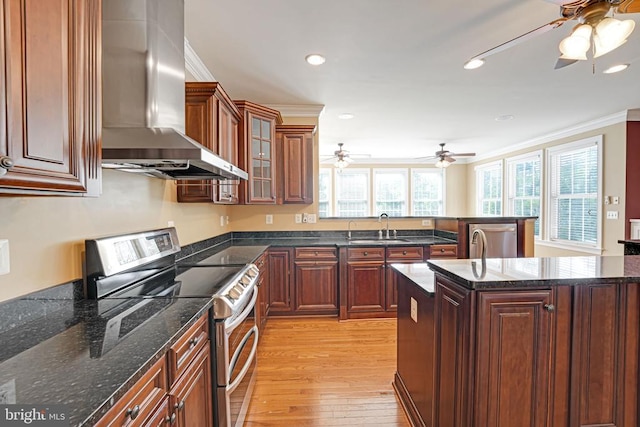 kitchen featuring a sink, wall chimney exhaust hood, a ceiling fan, and stainless steel appliances