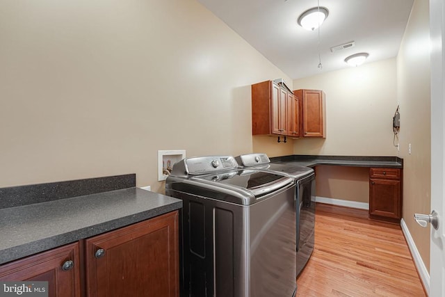 laundry room featuring light wood-type flooring, visible vents, washing machine and dryer, cabinet space, and baseboards