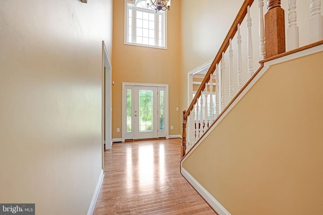 entrance foyer featuring stairway, wood finished floors, baseboards, and a chandelier