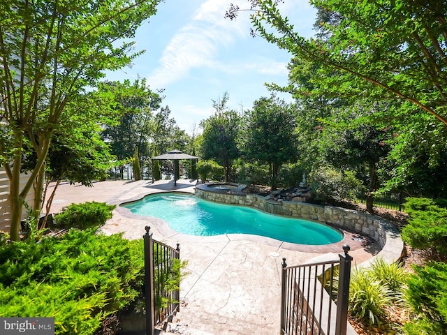 outdoor pool featuring a gazebo, a patio, an in ground hot tub, and fence