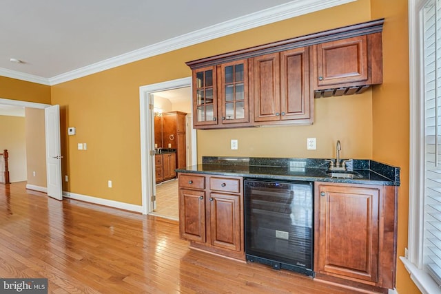 kitchen featuring a sink, wine cooler, crown molding, light wood finished floors, and baseboards