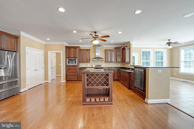 kitchen with a ceiling fan, dark countertops, wall chimney exhaust hood, and stainless steel fridge with ice dispenser