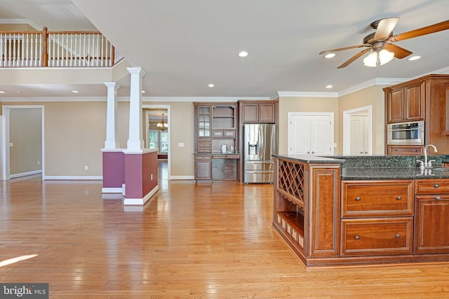 kitchen with a sink, a ceiling fan, light wood finished floors, and stainless steel appliances