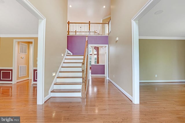 stairs featuring visible vents, wood finished floors, baseboards, and ornamental molding