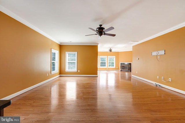 unfurnished living room featuring crown molding, wood finished floors, baseboards, and ceiling fan