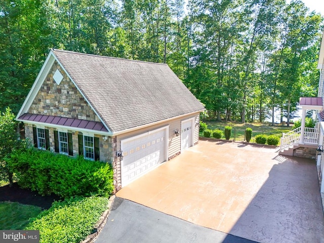 exterior space with a garage, stone siding, and a shingled roof