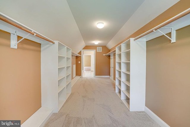 walk in closet with visible vents, lofted ceiling, and carpet