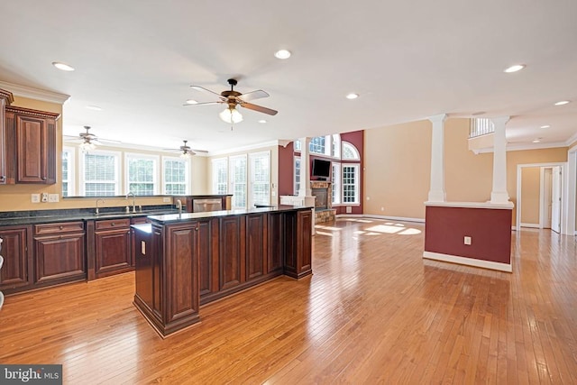 kitchen featuring dark countertops, light wood finished floors, open floor plan, and ornate columns