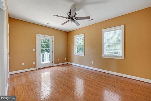 empty room featuring visible vents, ceiling fan, baseboards, and light wood-style floors