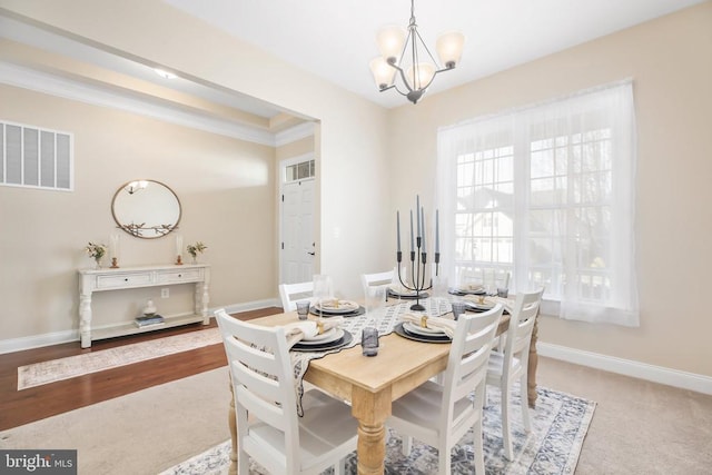 carpeted dining area with crown molding and an inviting chandelier