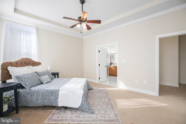 carpeted bedroom with connected bathroom, a tray ceiling, and ornamental molding