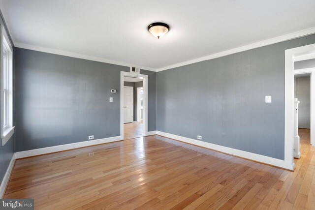 empty room with ornamental molding and light wood-type flooring