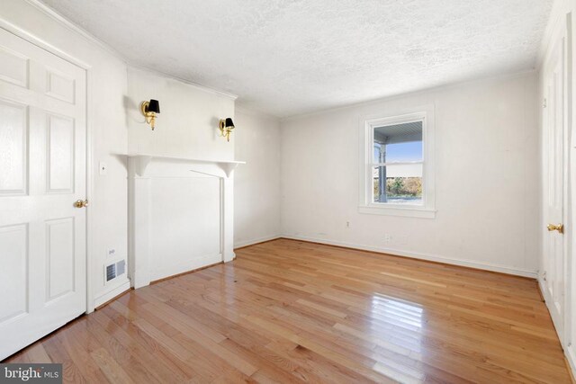 spare room with a textured ceiling and light wood-type flooring