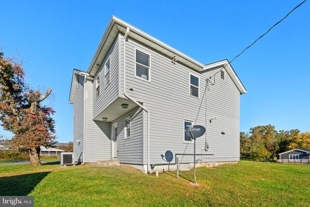 rear view of house with cooling unit and a lawn