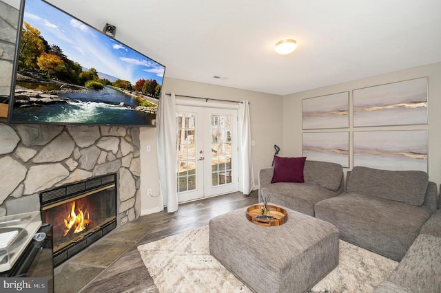 living room with french doors, a stone fireplace, and wood finished floors