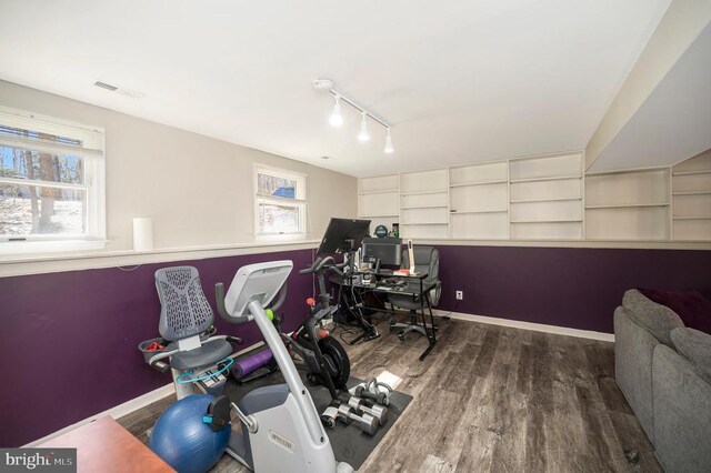 workout area featuring track lighting, wood finished floors, visible vents, and baseboards