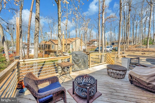 deck with area for grilling, a fire pit, and a residential view