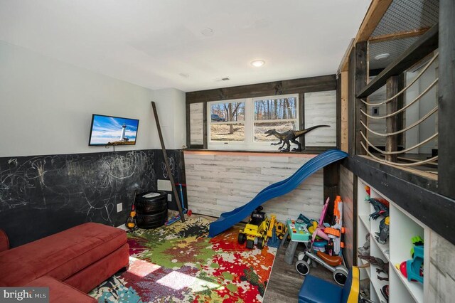 game room with wood finished floors and a wainscoted wall