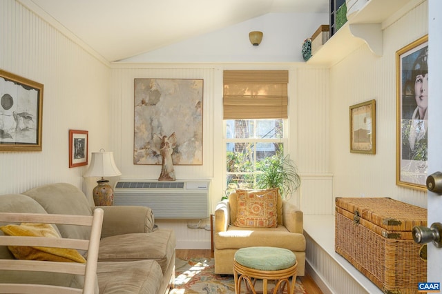 sitting room featuring vaulted ceiling, a wall mounted AC, and wood finished floors