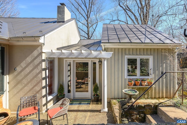 entrance to property featuring a standing seam roof, metal roof, a chimney, and board and batten siding