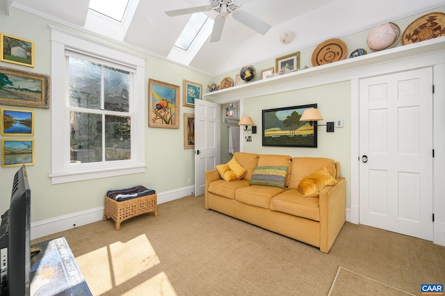 carpeted living area with lofted ceiling with skylight, a ceiling fan, and baseboards