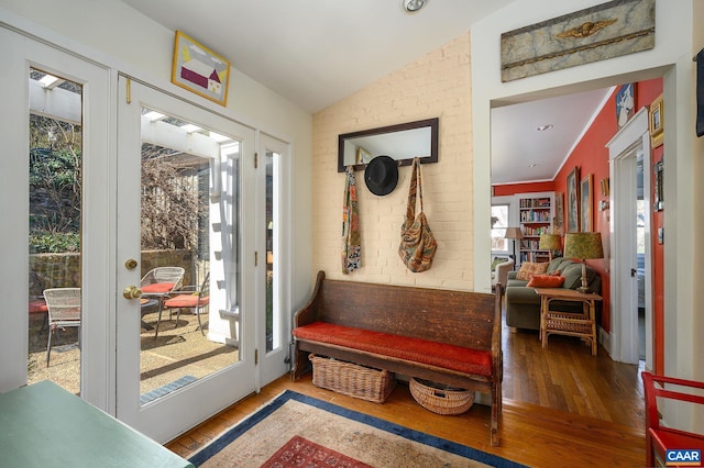 mudroom with vaulted ceiling, brick wall, and wood finished floors