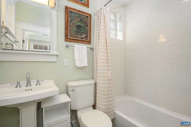 bathroom featuring shower / bath combination with curtain, a sink, and toilet