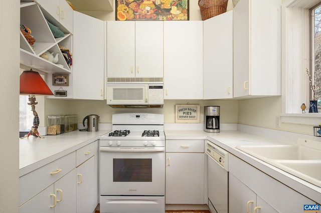 kitchen featuring white cabinets, white appliances, light countertops, and a sink